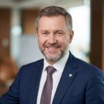 Портрет уверенного российского бизнесмена с дружелюбным взглядом на нейтральном фоне для сайта РусМед 24